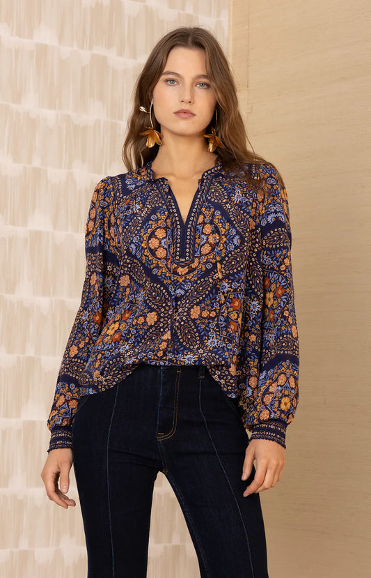 Woman wearing a patterned blouse against a neutral background