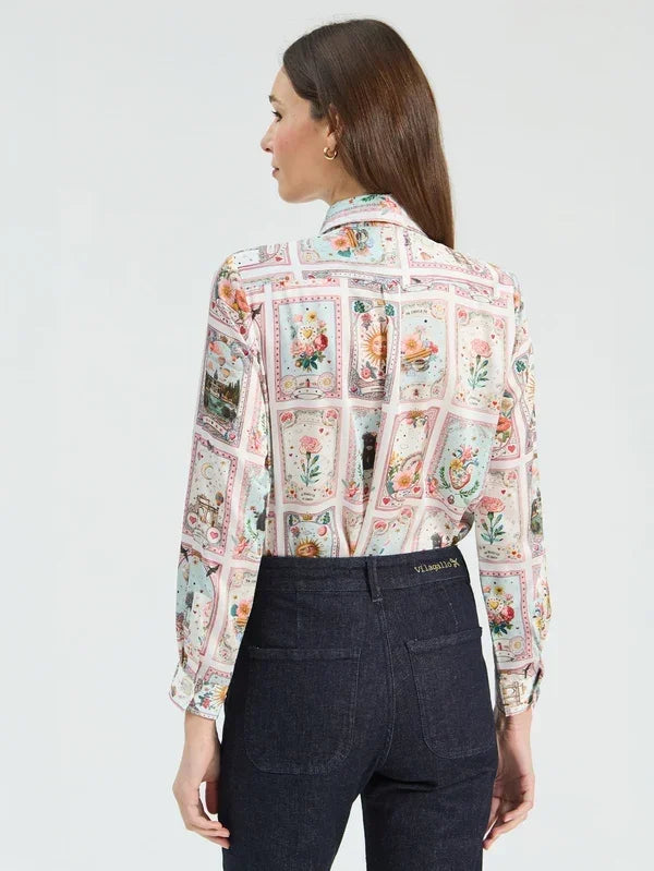 Woman wearing a luxury floral print long-sleeve silk blouse and dark denim jeans.