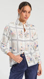 Woman wearing a white long-sleeve floral print button-down shirt and navy corduroy trousers.