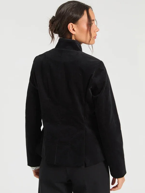 Woman wearing a luxury black velvet blazer jacket, back view.