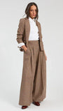 Woman wearing a brown checked blazer and matching wide-leg trousers with a white shirt.