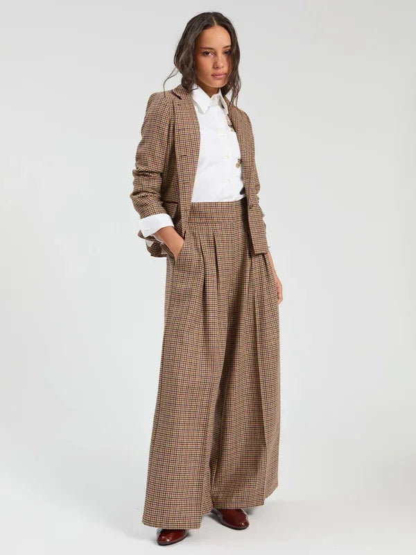 Woman wearing a brown checked blazer and matching wide-leg trousers with a white shirt.