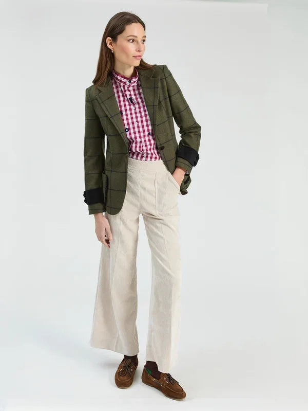 Woman wearing a green plaid blazer, pink gingham shirt, and cream wide-leg trousers.