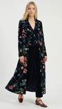 Woman wearing a luxury navy blue floral velvet long coat and matching wide-leg trousers.
