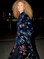 Woman wearing a luxury navy blue velvet floral embroidered long coat at night.