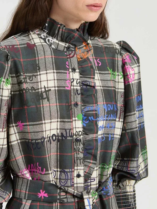 Woman wearing a high-neck plaid designer dress with colorful graffiti print.