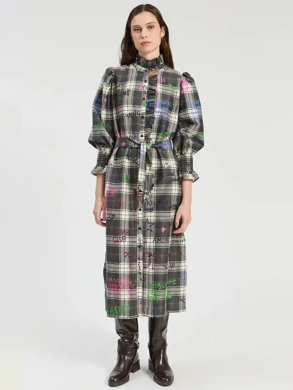 Woman wearing a long plaid designer dress with colorful graffiti print and puffed sleeves.