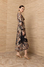Woman wearing a long-sleeved black maxi dress with an intricate bohemian paisley print.