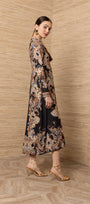 Woman wearing a long-sleeved black maxi dress with an intricate bohemian paisley print.