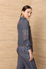Woman wearing a blue patterned designer blouse and matching trousers in a luxury style.