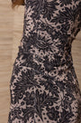 Woman wearing a luxury black and beige floral print ruched designer dress.