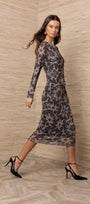 Woman wearing a long-sleeved floral print midi dress and black high heel sandals.