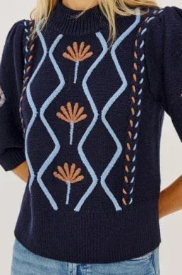 Navy blue knit sweater with light blue geometric patterns and orange floral embroidery