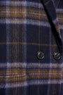Close-up of a luxury women's plaid wool blazer in navy and brown with black buttons.