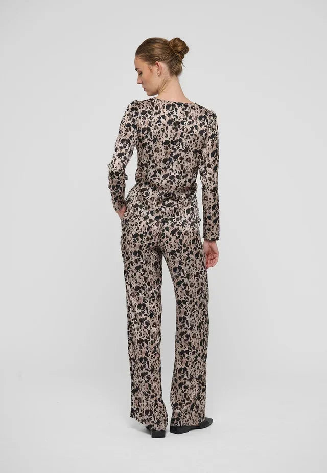 Rear view of a woman wearing a leopard print long sleeve jumpsuit with wide legs.