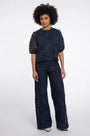 Woman wearing a navy blue lace two-piece set with a short-sleeve top and wide-leg trousers.