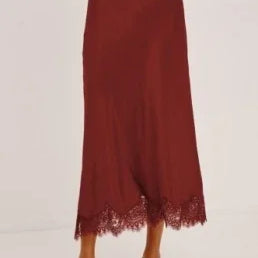 Woman wearing a burgundy midi skirt with lace trim and black strappy heels