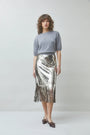 Woman wearing a grey knit sweater and a silver sequined midi skirt with fringe hem.