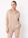 Woman wearing a beige cashmere hoodie and matching knit trousers