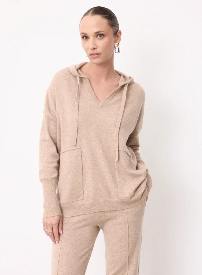 Woman wearing a beige cashmere hoodie and matching knit trousers