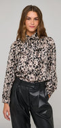 Woman wearing a leopard print long-sleeve blouse with a pussy bow neck and black leather trousers.