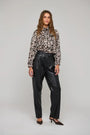 Woman wearing a leopard print long sleeve blouse and black faux leather trousers.