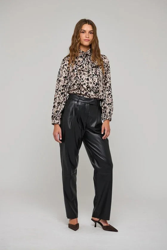 Woman wearing a leopard print long sleeve blouse and black faux leather trousers.