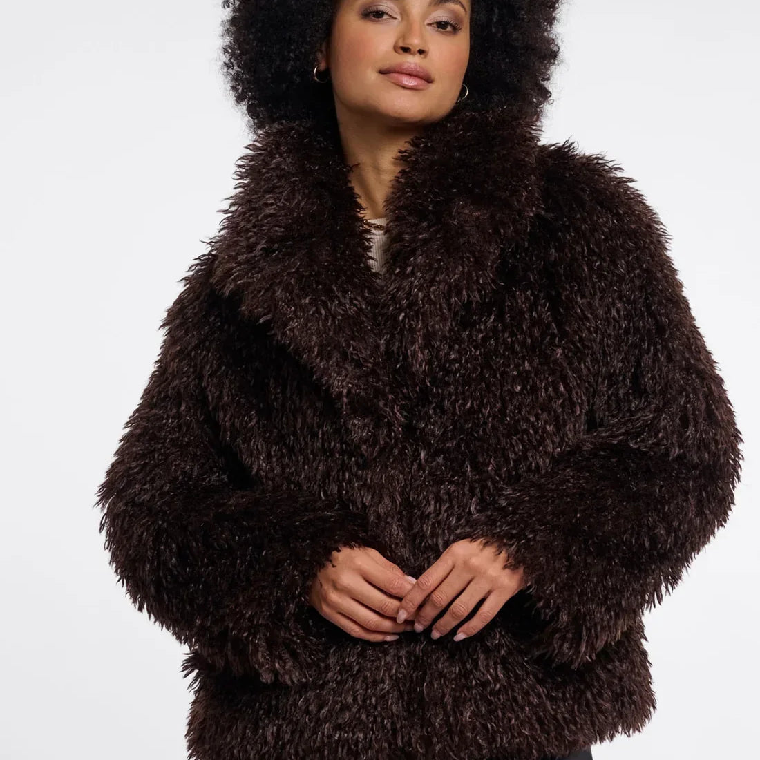 Woman with afro hair wearing a luxury dark brown faux fur coat and black leather trousers