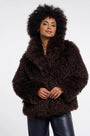 Woman with afro hair wearing a luxury dark brown faux fur coat and black leather trousers