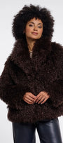 Woman with afro hair wearing a luxury dark brown faux fur coat and black leather trousers