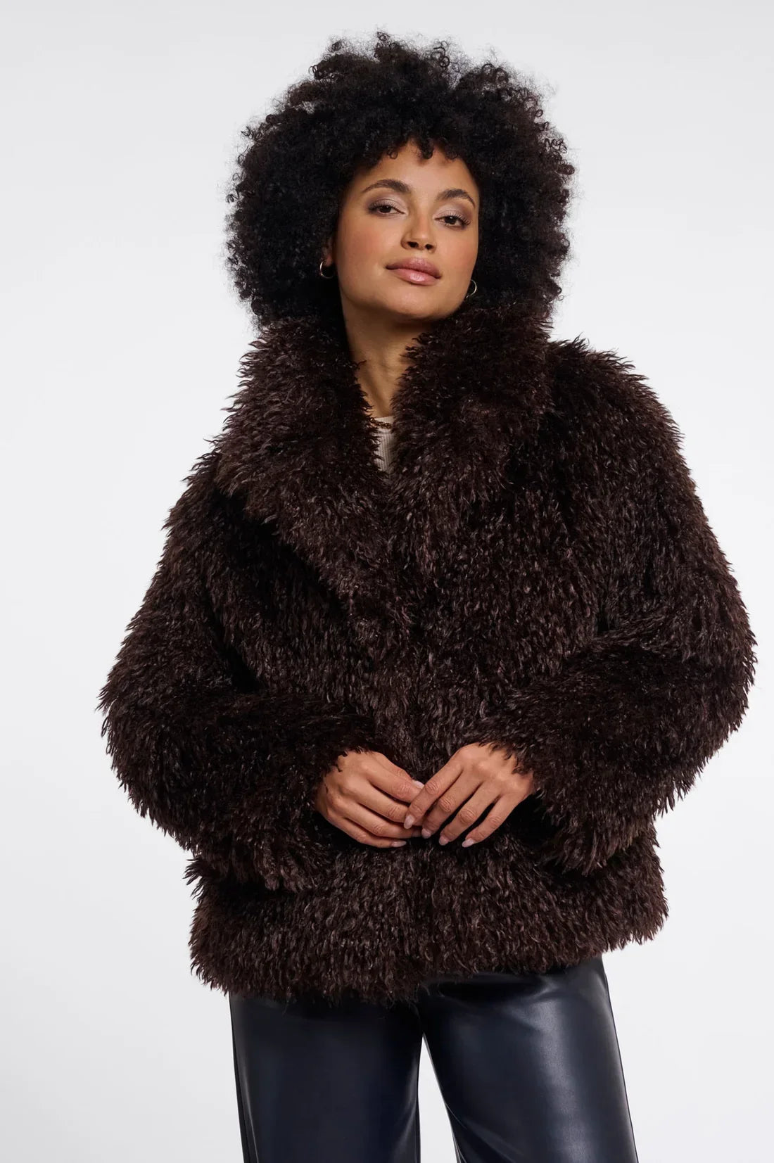 Woman with afro hair wearing a luxury dark brown faux fur coat and black leather trousers