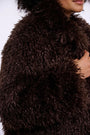 Close-up of a woman wearing a luxury dark brown faux fur coat.