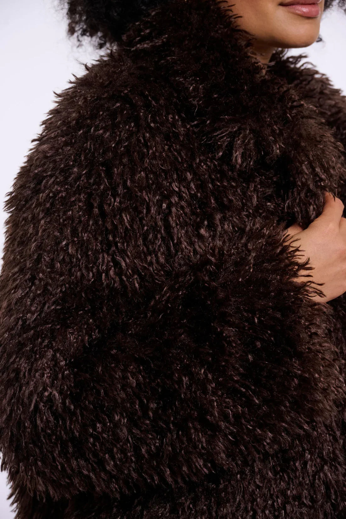Close-up of a woman wearing a luxury dark brown faux fur coat.