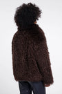Back view of a woman wearing a brown faux fur jacket and black leather trousers