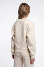 Back view of a woman wearing a cream designer sweatshirt with floral embroidery on the sleeve.