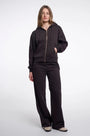 Woman wearing a luxury black zip-up hoodie and matching wide-leg trousers set.
