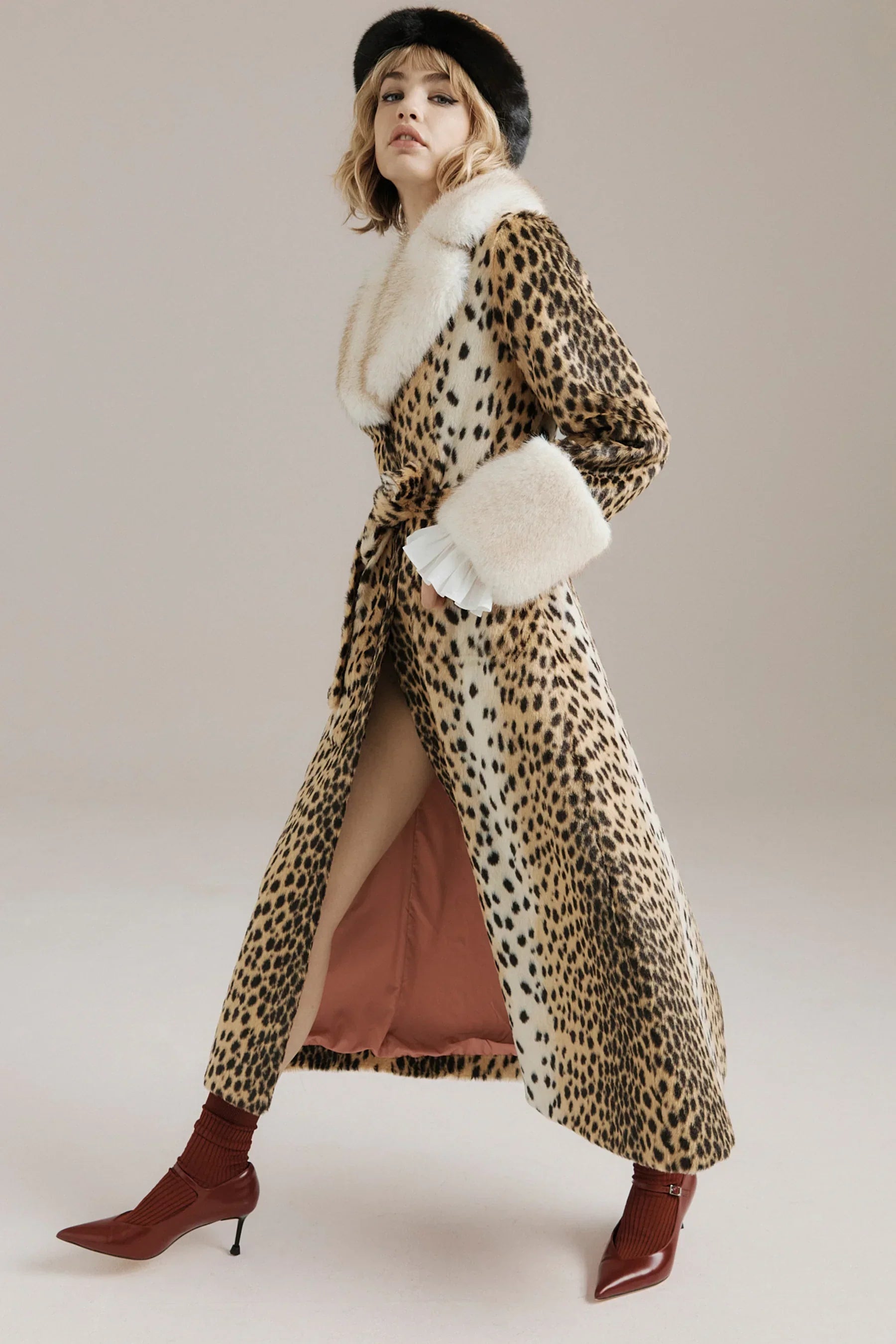 Woman wearing a luxury leopard print coat with white fur collar and matching black fur hat.