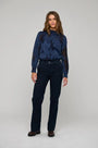 Woman wearing a blue floral textured blouse and navy blue trousers.