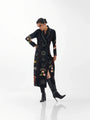 Woman wearing a black long-sleeved celestial print maxi dress and black high-heeled boots.