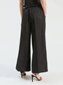 Rear view of a woman wearing black wide-leg trousers with subtle silver shimmer and black heels