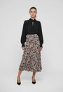 Woman wearing a black long-sleeve blouse and a patterned midi skirt with black pumps.
