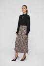 Woman wearing a black long-sleeve blouse and a leopard print midi skirt with black heels.