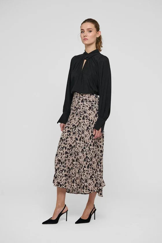Woman wearing a black long-sleeve blouse and a leopard print midi skirt with black heels.