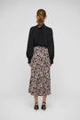 Woman wearing a black long-sleeve blouse and a pink and black animal print midi skirt.