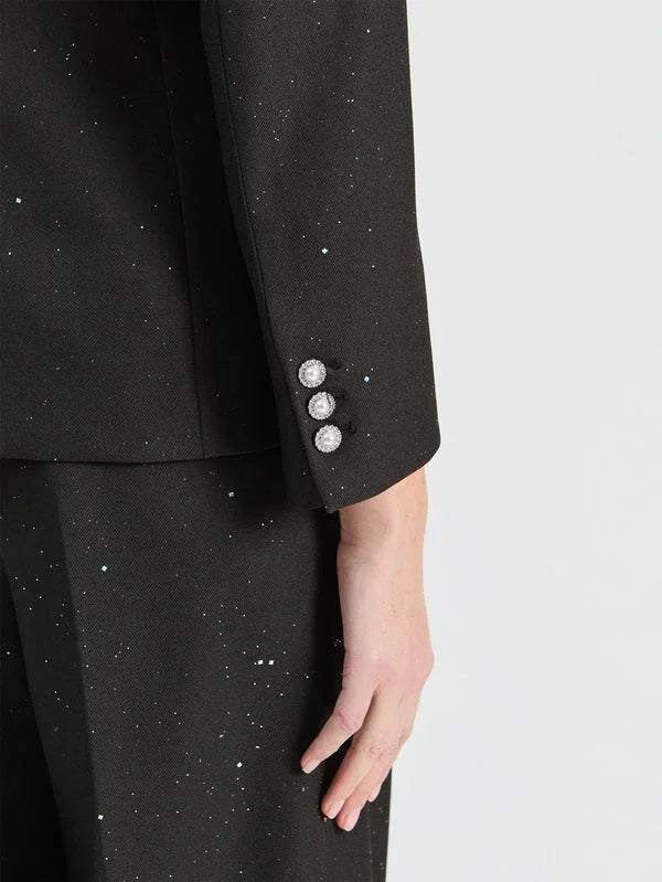 Close-up of a black sparkly designer suit jacket sleeve with three crystal buttons.