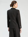 Back view of a woman wearing a black sparkle-detailed designer blazer and matching trousers.
