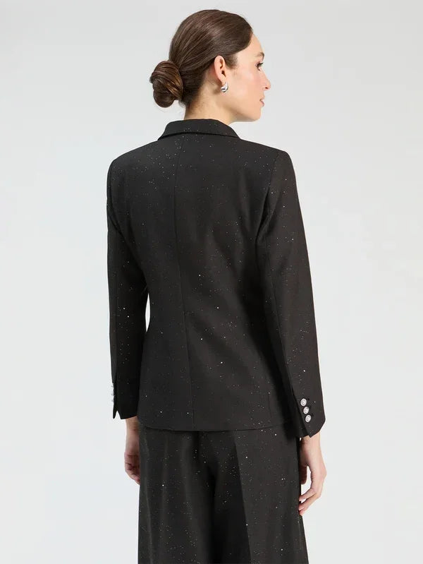 Back view of a woman wearing a black sparkle-detailed designer blazer and matching trousers.