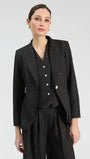 Woman wearing a black three-piece suit with subtle white speckles, including a blazer, vest, and trousers.